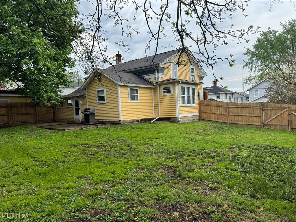 Rear view of property with a lawn, a gate, a chimney, and a fenced backyard