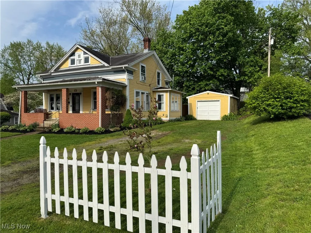 View of front of property with covered porch, fence private yard, an outdoor structure, and a front lawn