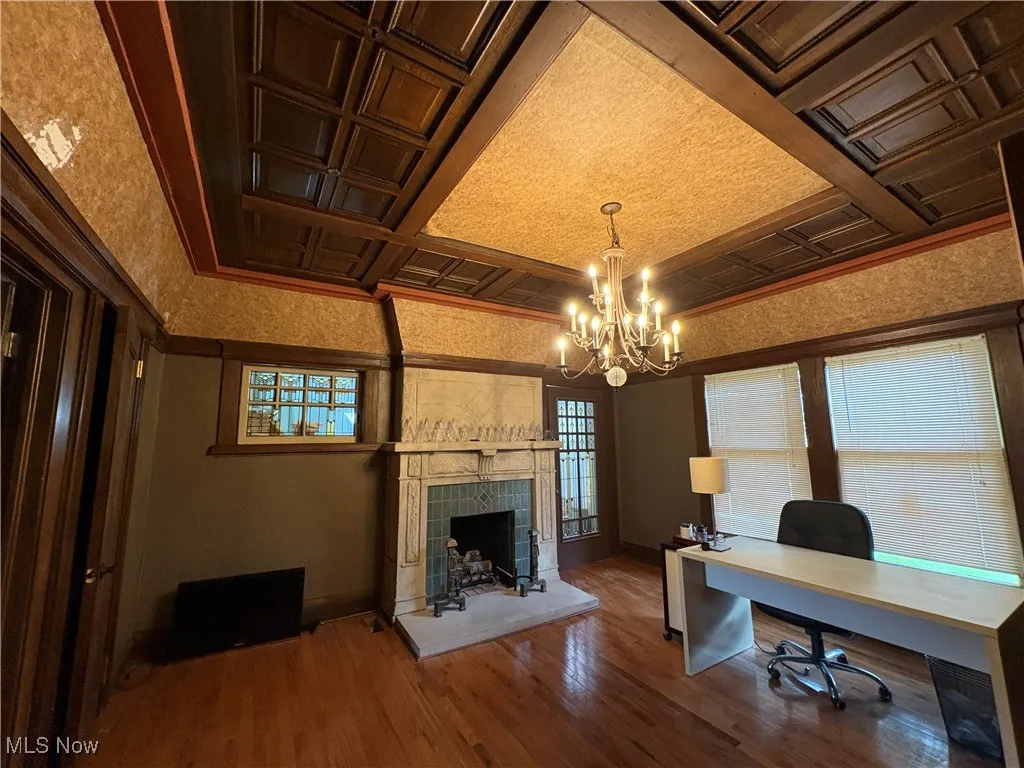 Office featuring baseboards, a notable chandelier, wood finished floors, and a tile fireplace