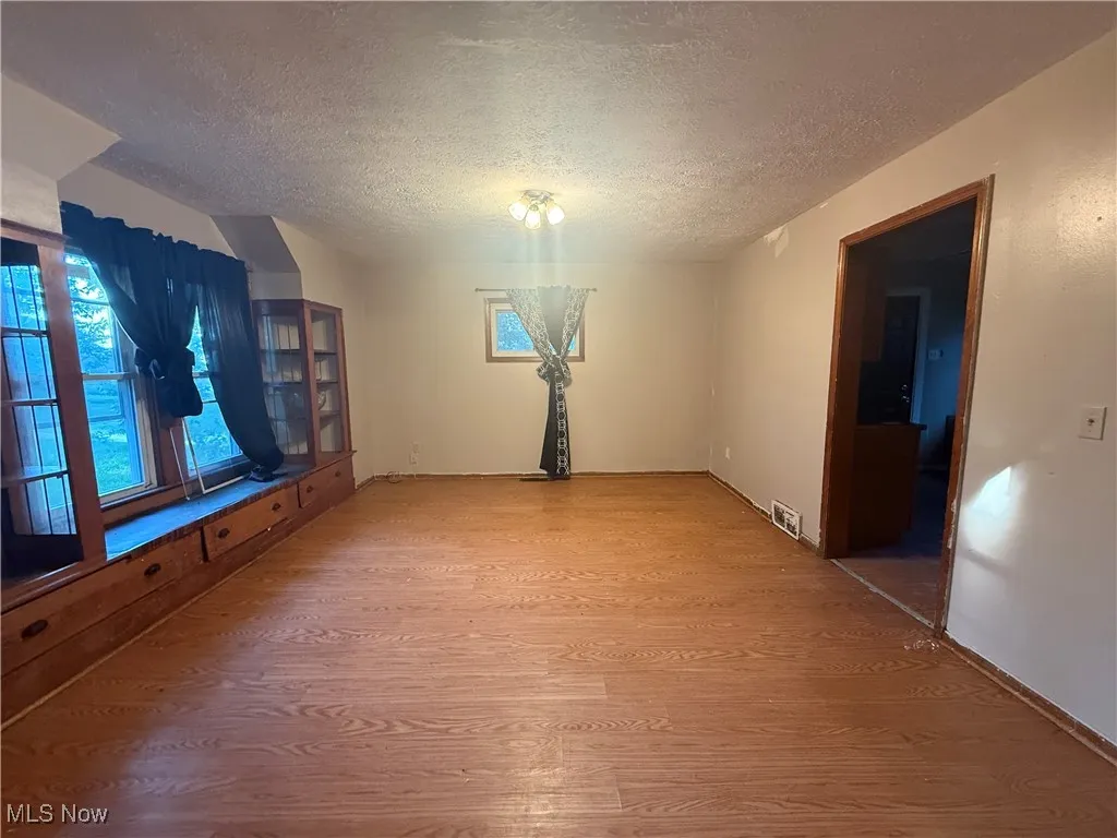 Unfurnished dining area featuring wood finished floors and a textured ceiling