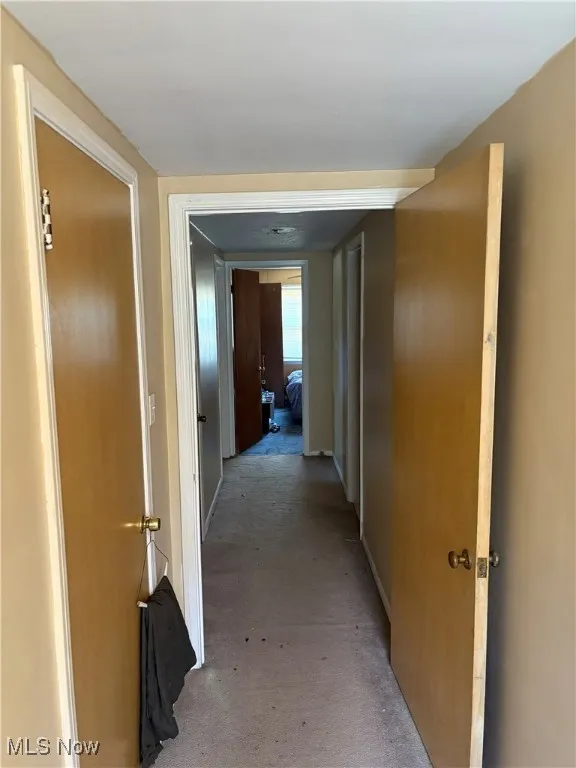 Hallway featuring light colored carpet and baseboards