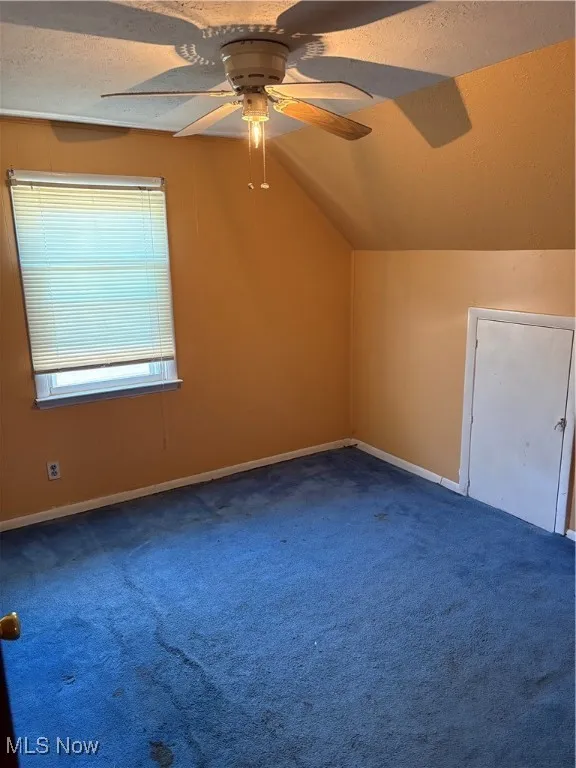 Bonus room featuring a ceiling fan, vaulted ceiling, a textured ceiling, and carpet