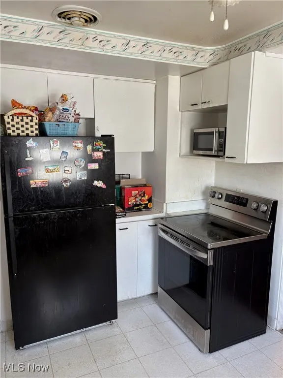 Kitchen with visible vents, appliances with stainless steel finishes, light tile patterned floors, and white cabinets