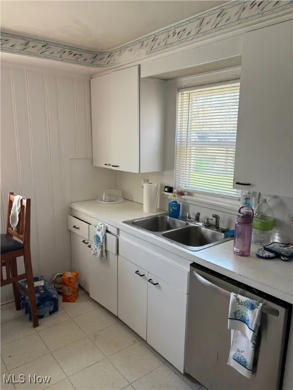 Kitchen featuring a sink, light countertops, white cabinets, and dishwasher
