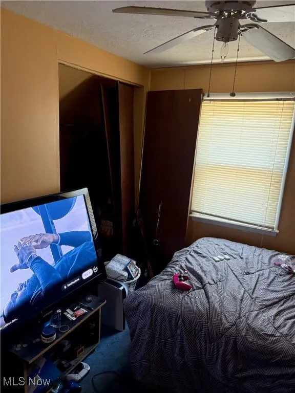 Carpeted bedroom featuring a closet, a textured ceiling, and ceiling fan