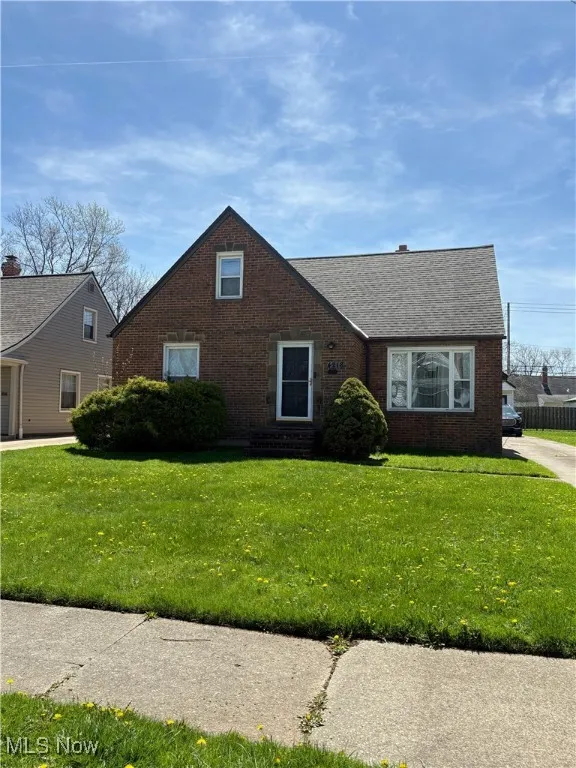 View of front of home with entry steps, a shingled roof, a front lawn, and brick siding
