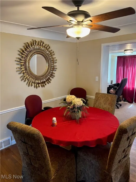 Dining area with a ceiling fan, visible vents, and wood finished floors