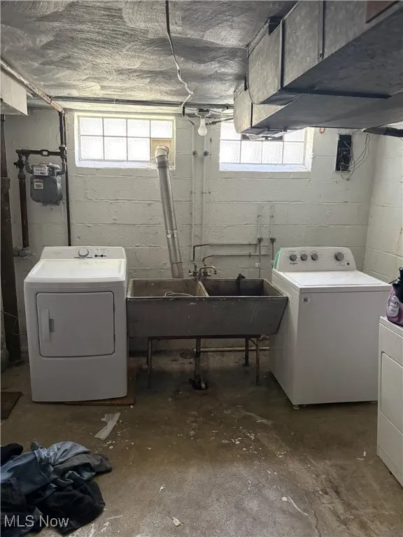 Clothes washing area with a sink, separate washer and dryer, and laundry area
