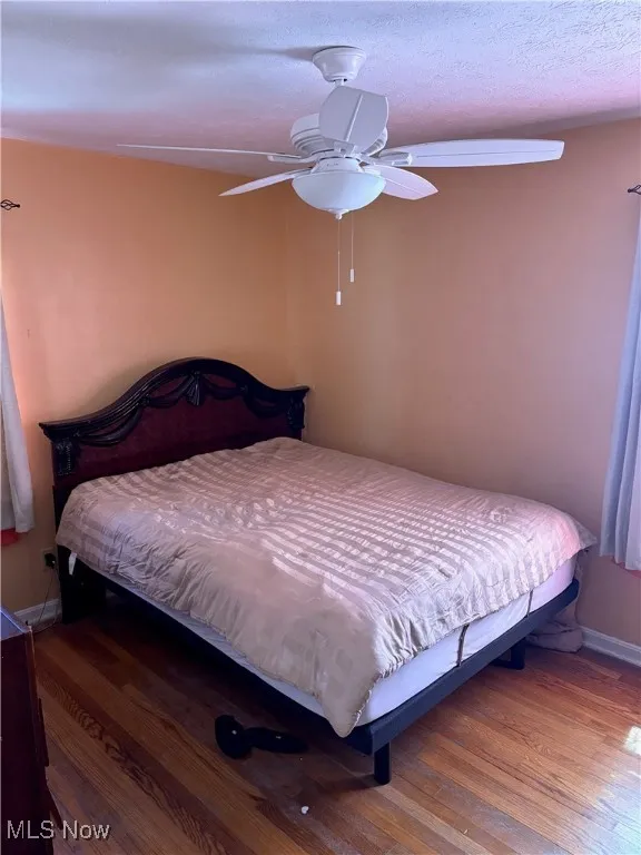 Bedroom featuring baseboards, a ceiling fan, and wood finished floors