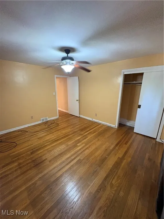 Unfurnished bedroom featuring ceiling fan, a closet, wood finished floors, and a textured ceiling