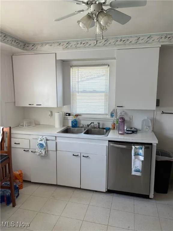 Kitchen featuring light countertops, white cabinets, a sink, and dishwasher