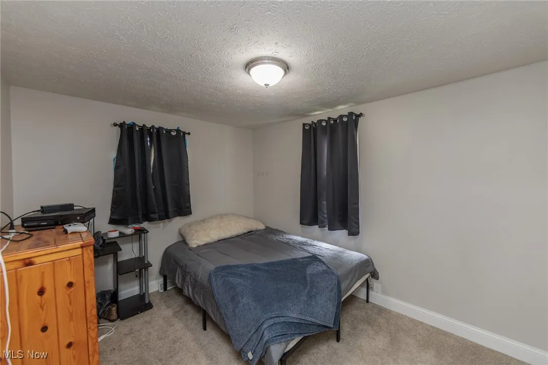 Carpeted bedroom featuring baseboards and a textured ceiling