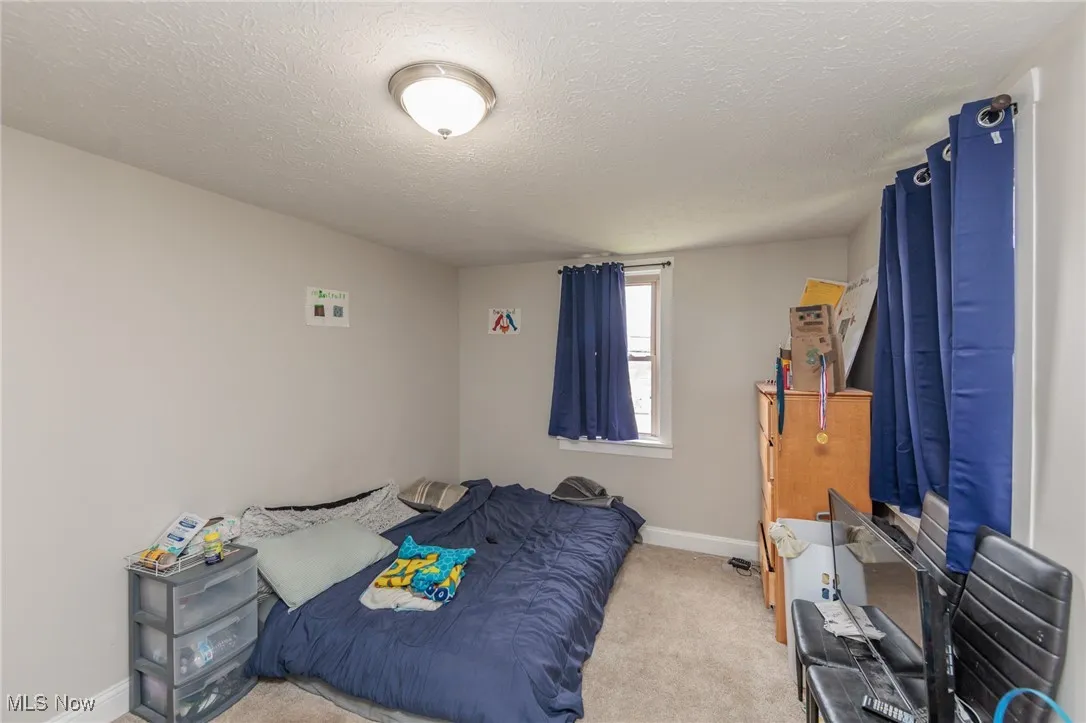 Carpeted bedroom featuring baseboards and a textured ceiling