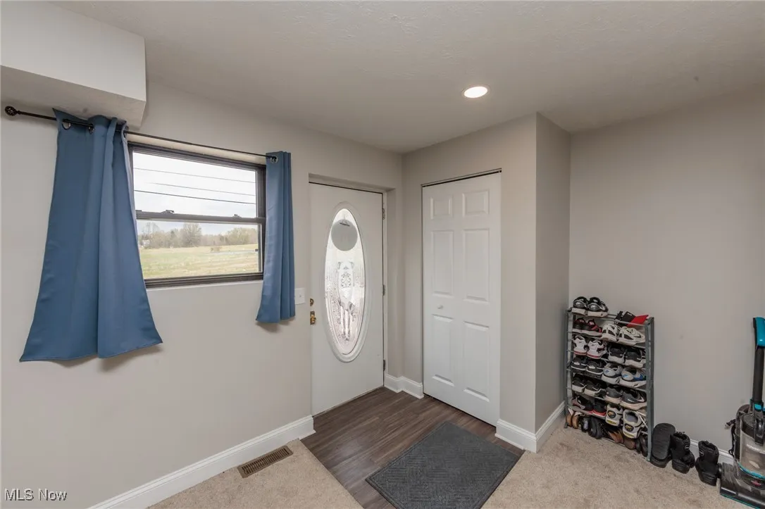 Carpeted foyer featuring visible vents, recessed lighting, and baseboards
