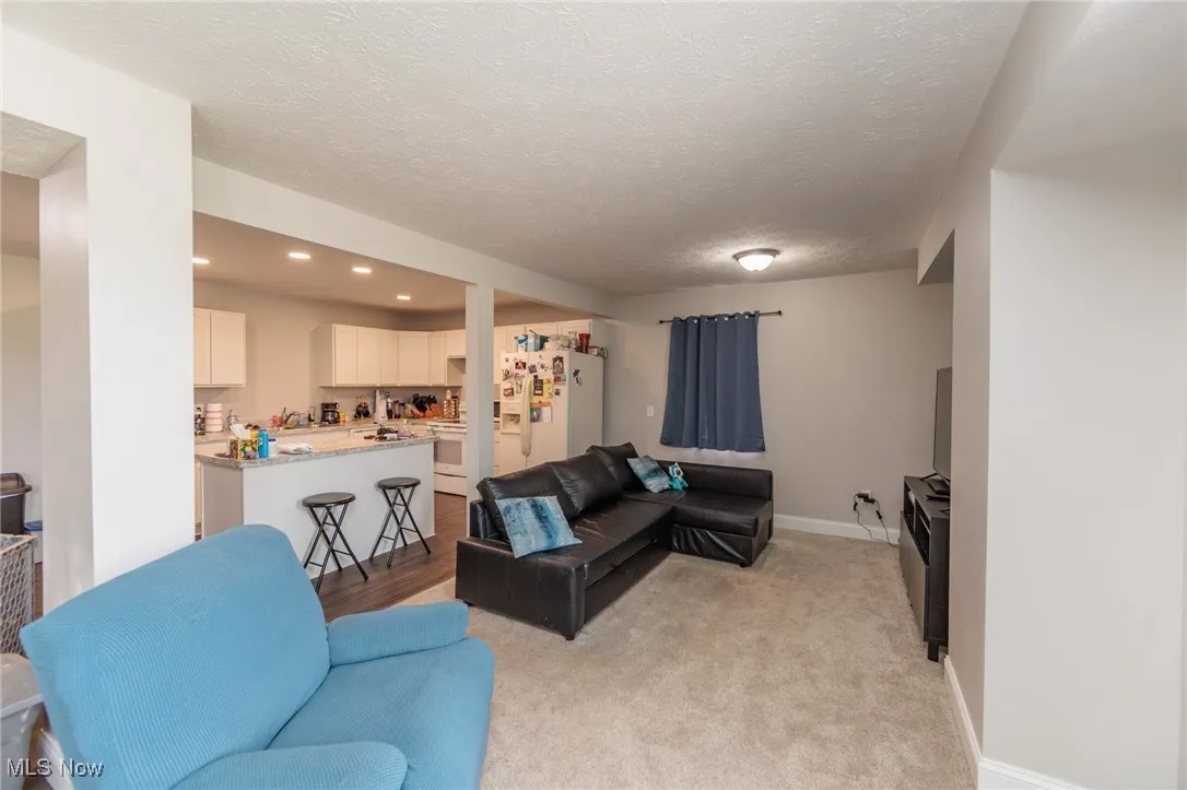 Living room featuring recessed lighting, a textured ceiling, light carpet, and baseboards