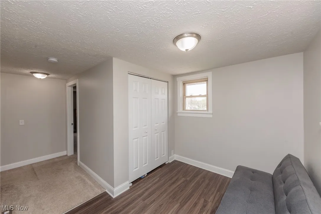 Unfurnished room with baseboards, dark wood-style floors, and a textured ceiling