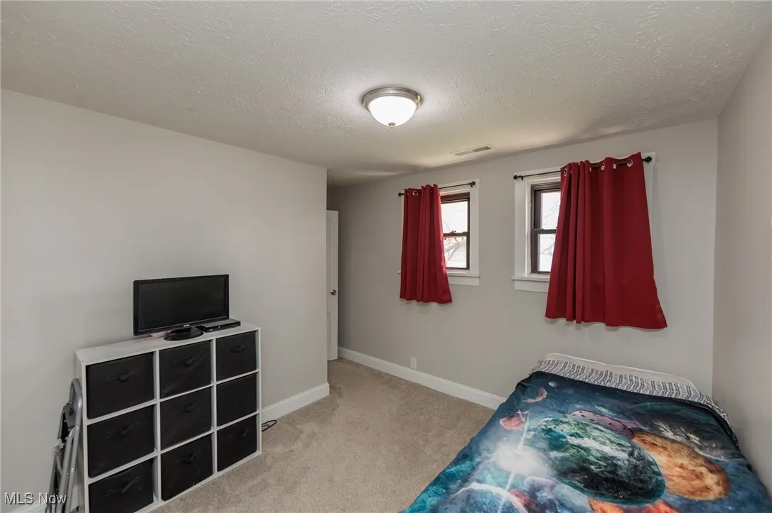 Unfurnished bedroom featuring carpet flooring, a textured ceiling, baseboards, and visible vents