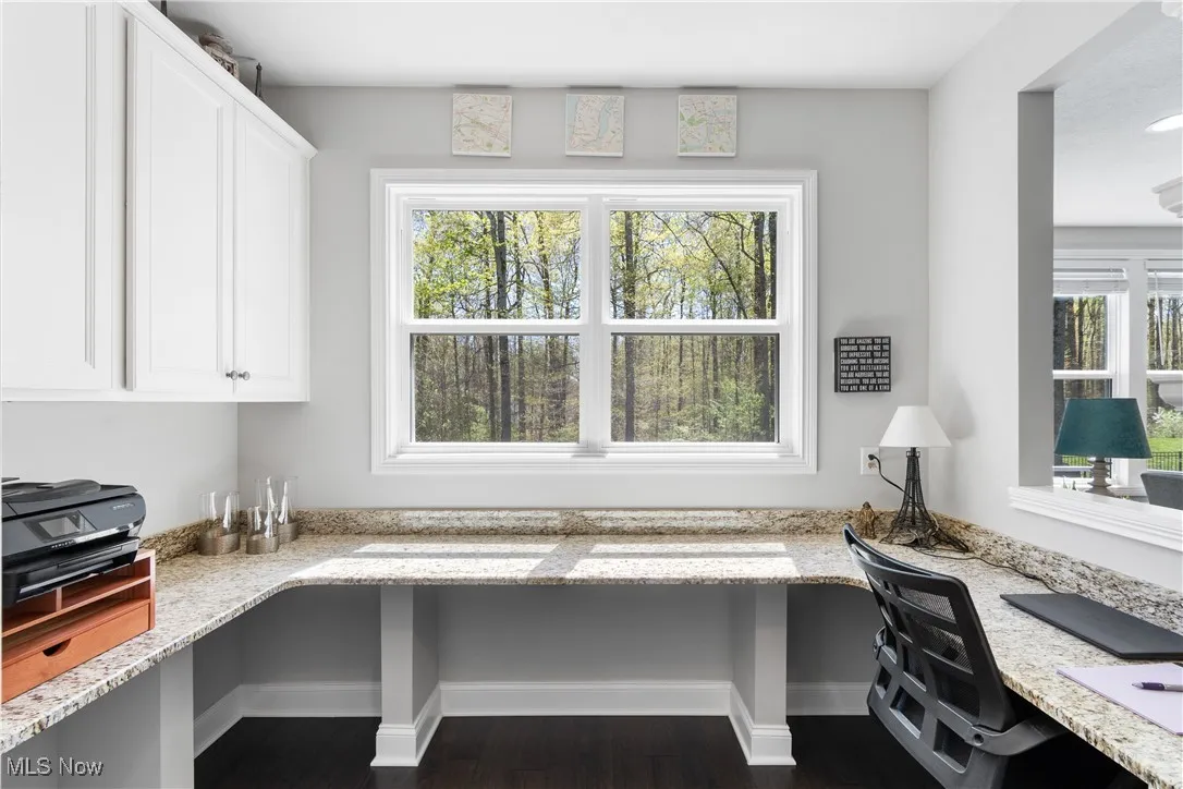 Home office with baseboards, dark wood-style floors, and built in desk