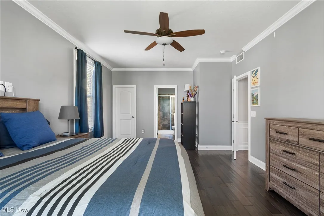 1st floor Bedroom featuring crown molding, ceiling fan, baseboards, dark wood-type flooring, and visible vents