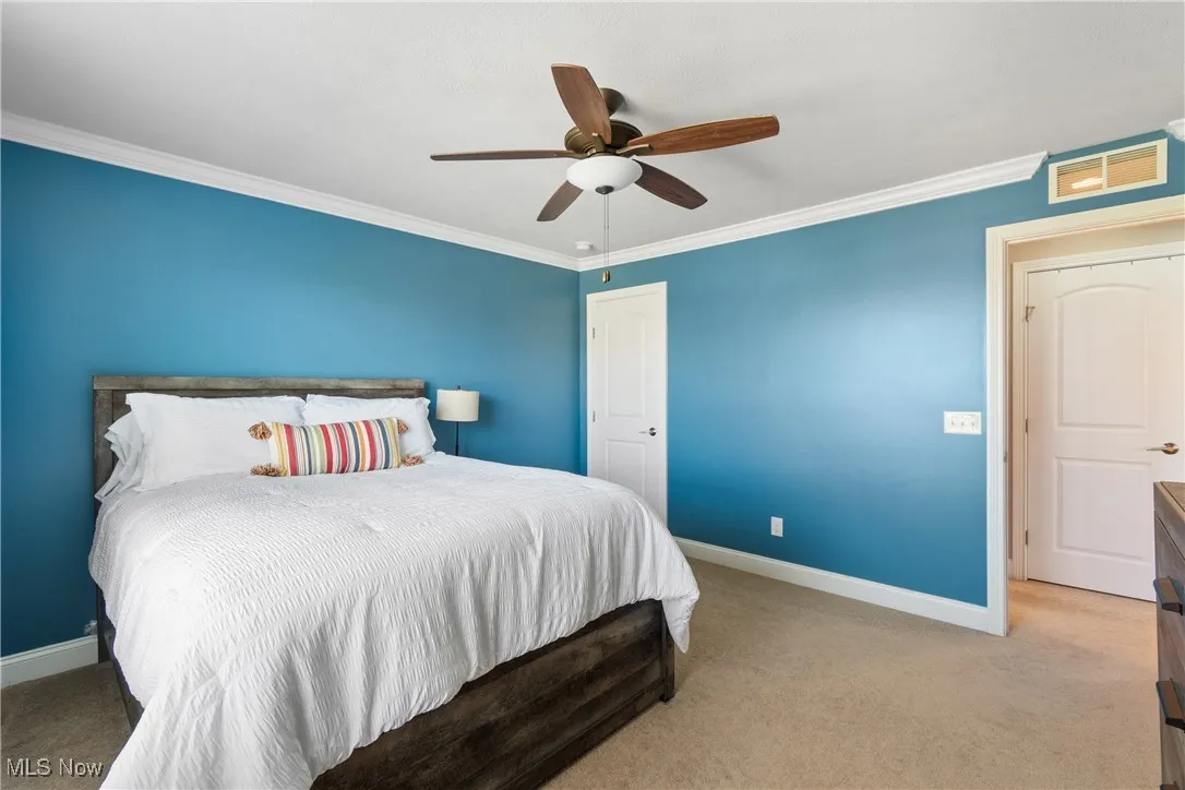 Bedroom with carpet floors, baseboards, visible vents, and ornamental molding