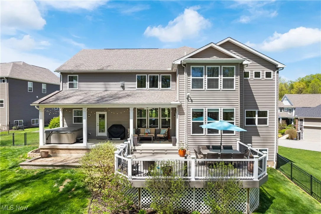 Rear view of property featuring a fenced backyard, a yard, a hot tub, and a deck