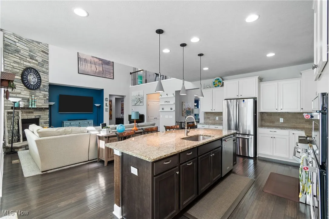 Kitchen featuring white cabinets, dark brown cabinetry, appliances with stainless steel finishes, a sink, and decorative backsplash
