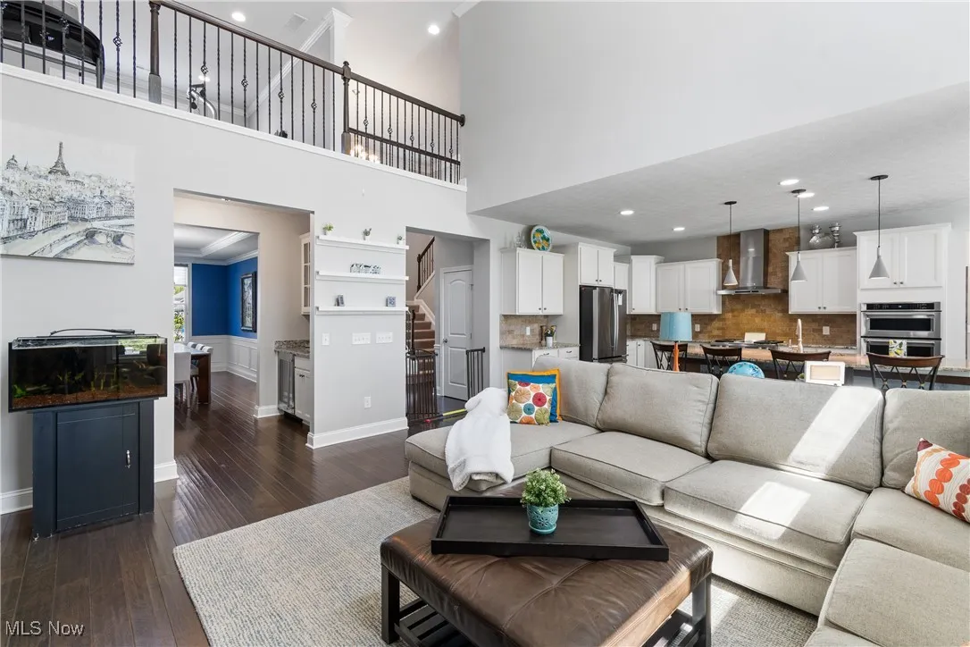 Living room featuring stairs, recessed lighting, baseboards, a towering ceiling, and dark wood-type flooring