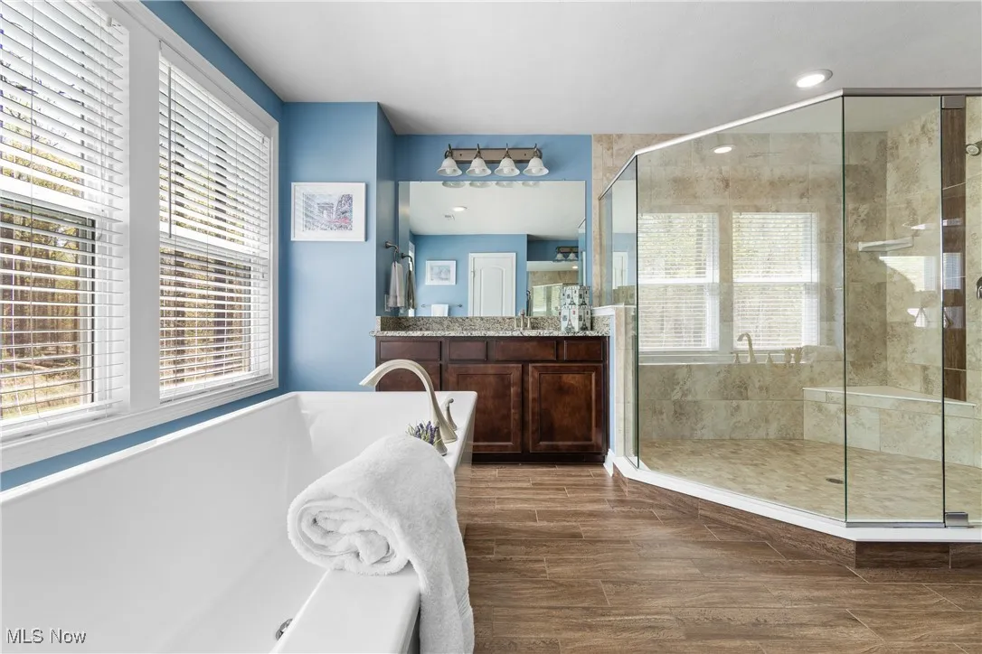 Bathroom featuring a tub, a shower stall, and a wealth of natural light