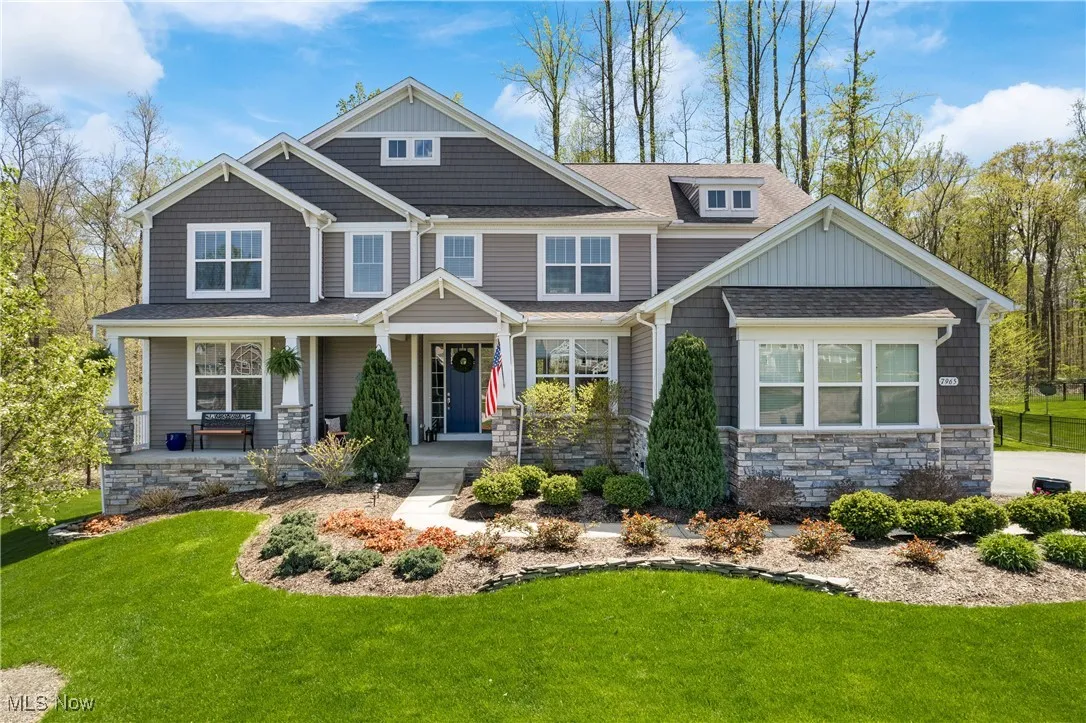 Craftsman house with a porch, a shingled roof, stone siding, and a front lawn