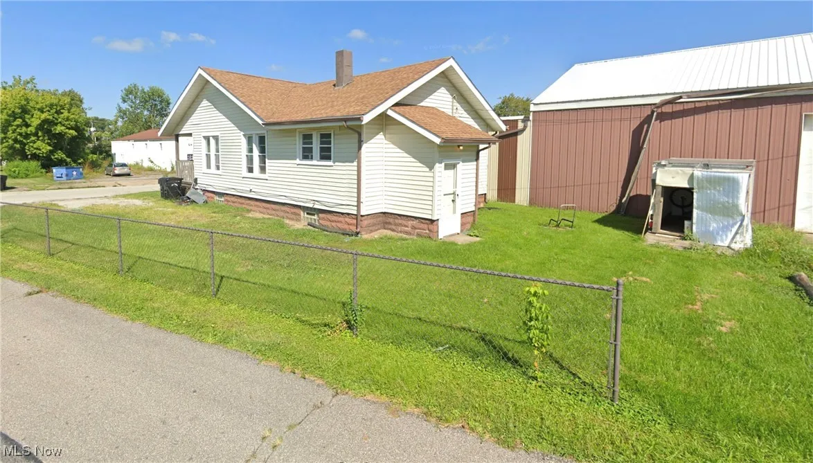 View of home's exterior featuring a fenced backyard, a lawn, and roof with shingles