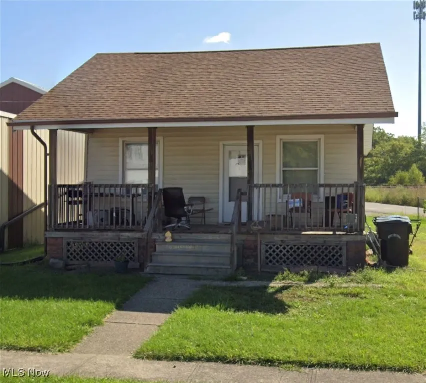 Bungalow featuring a porch, roof with shingles, and a front yard