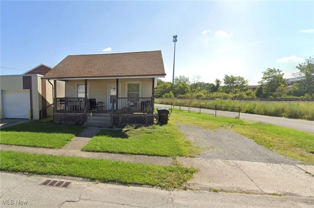 Bungalow-style home featuring fence, a front yard, roof with shingles, a porch, and driveway