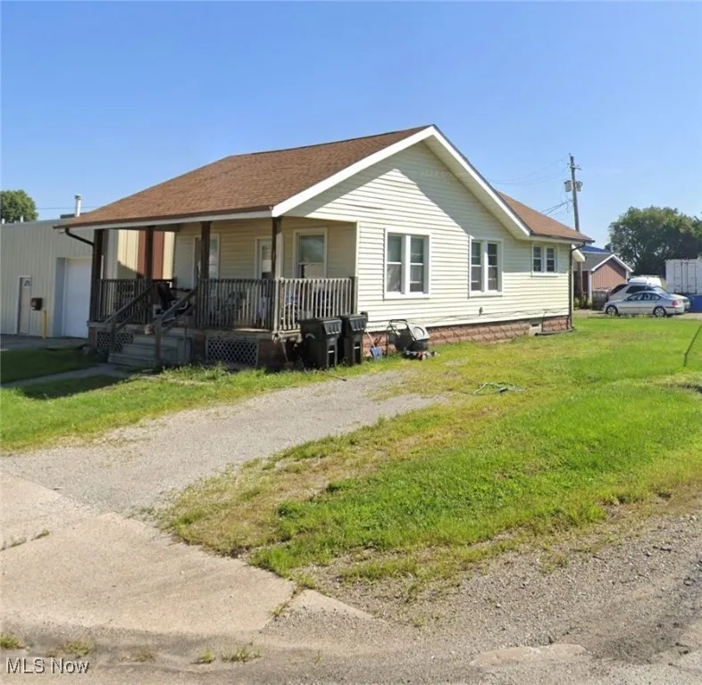 View of front of house featuring a porch, driveway, a front yard, a garage, and a shingled roof