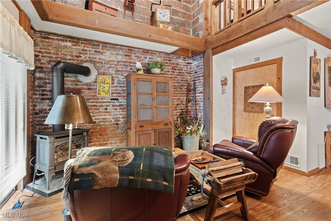 Great room in rear unit featuring wood-burning stove, original exposed brick walls and beams, sliding glass door to back courtyard patio.