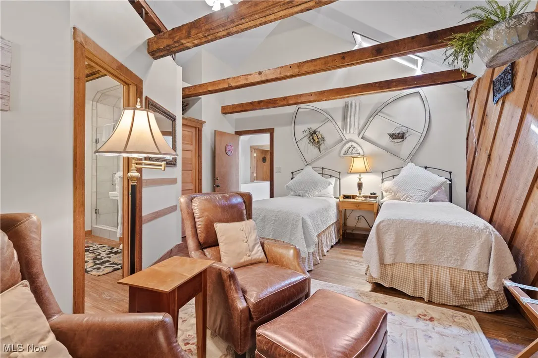 Bedroom featuring vaulted ceiling with beams and light wood-style floors