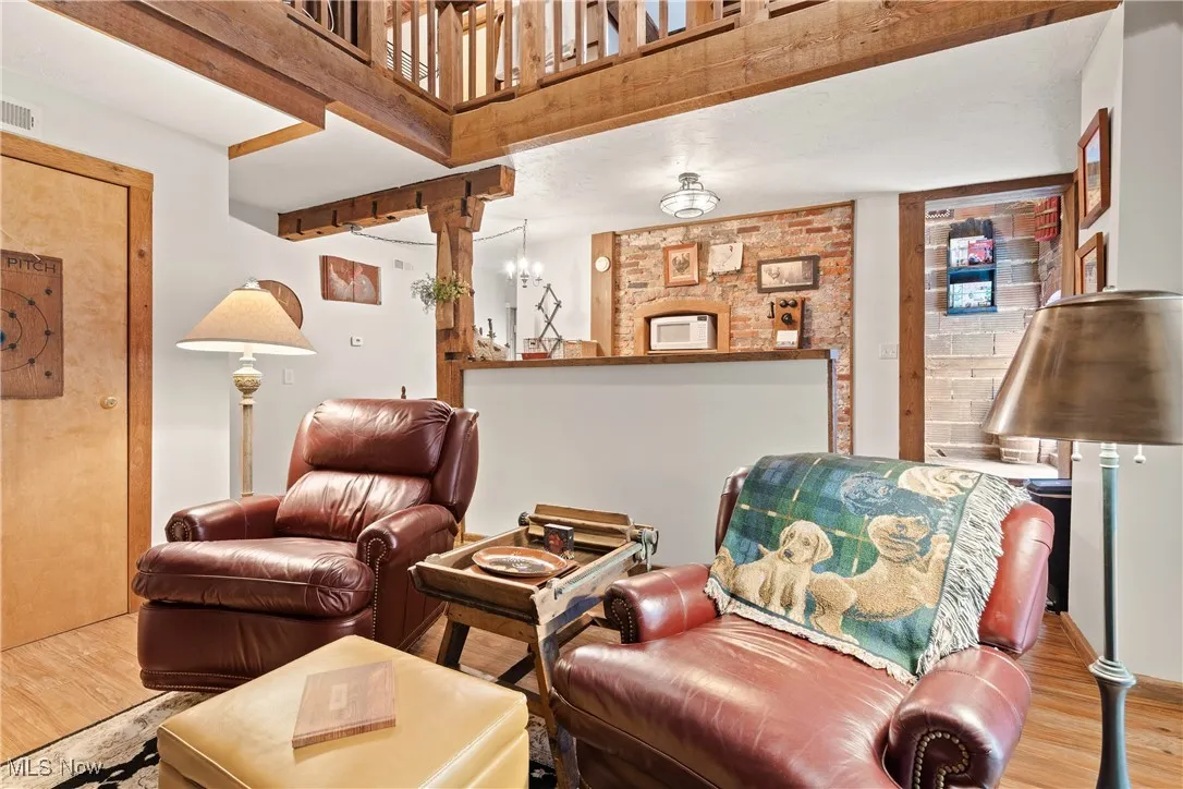 Great room in rear unit with original beams and exposed brick walls looking towards the kitchen and stairwell to the 2nd floor