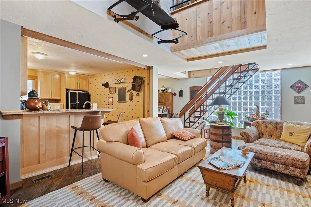 Living room with recessed lighting, baseboards, wood finished floors, visible vents, and stairway