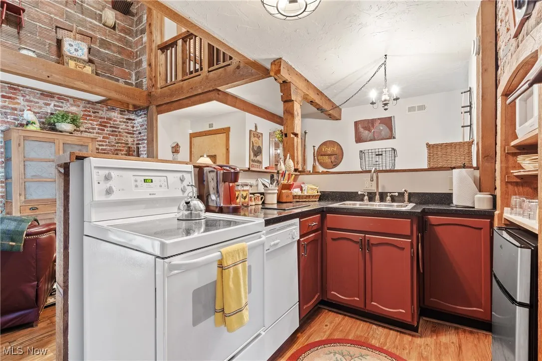 Rear unit Kitchen with electric range, dishwasher, granite countertops, and insert in the exposed brick wall with mini refrigerator/freezer. Insert can accommodate a standard size retro refrigerator