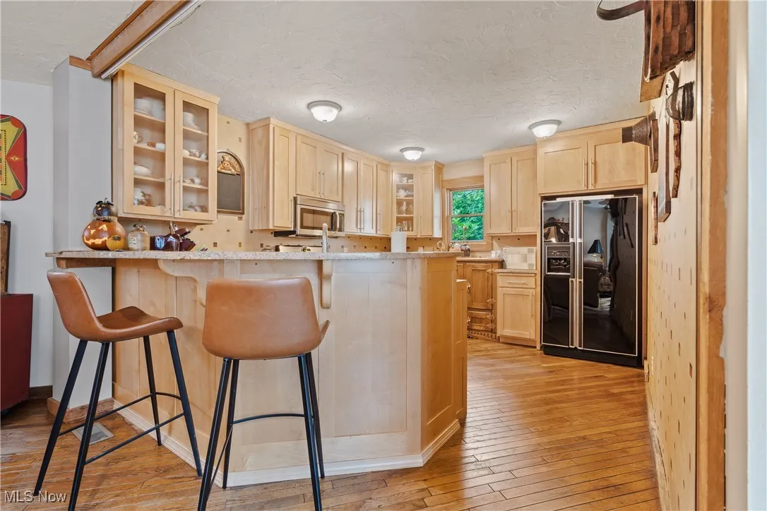 Updated Kitchen for the front unit featuring a refrigerator, gas range, microwave/hood, dishwasher, maple cabinets, and granite countertops