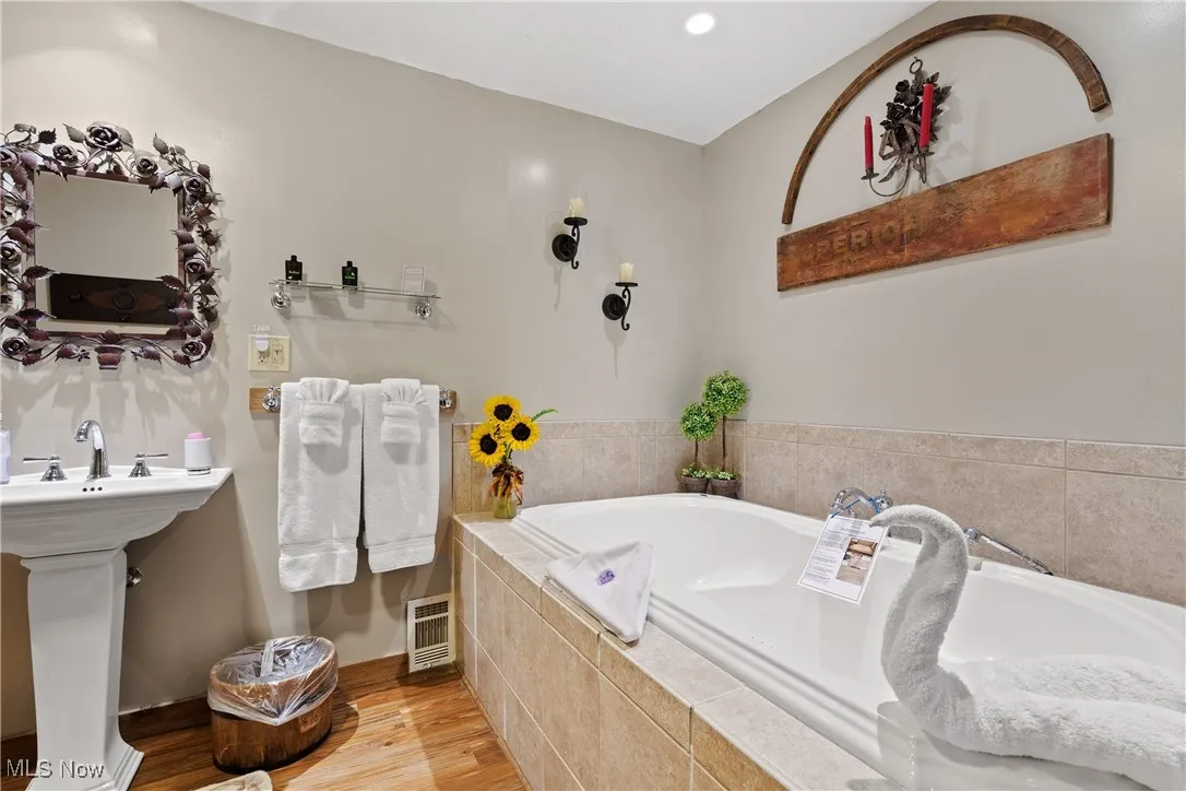 Bathroom with wood finished floors and a garden tub
