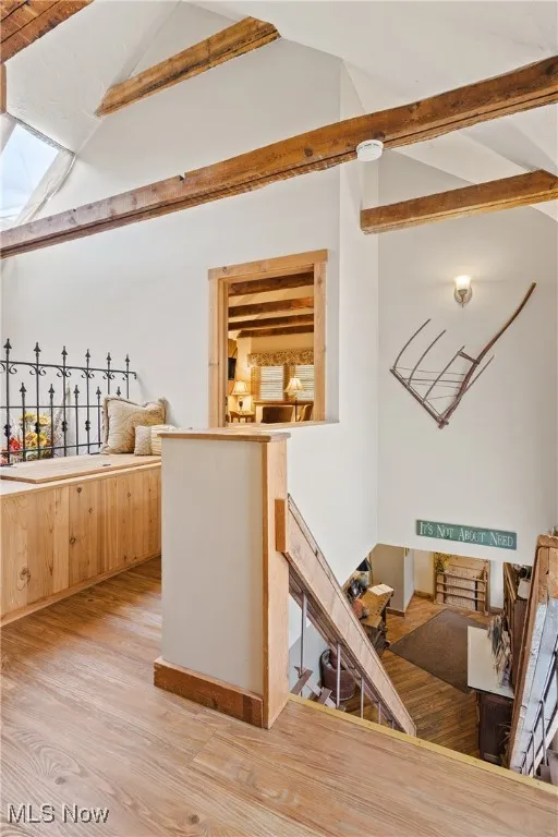 Bar featuring light wood-type flooring and lofted ceiling with beams