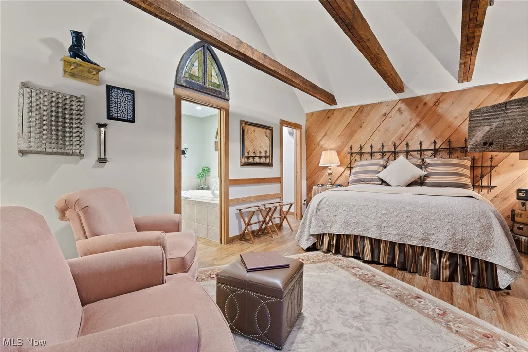 Bedroom with wooden walls, high vaulted ceiling, beam ceiling, and wood finished floors