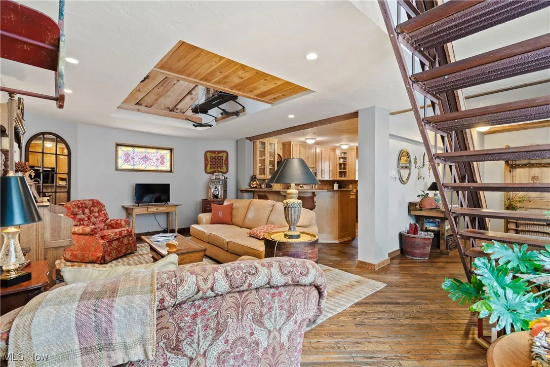 Living room with hardwood / wood-style flooring, stairs, baseboards, a raised ceiling, and recessed lighting