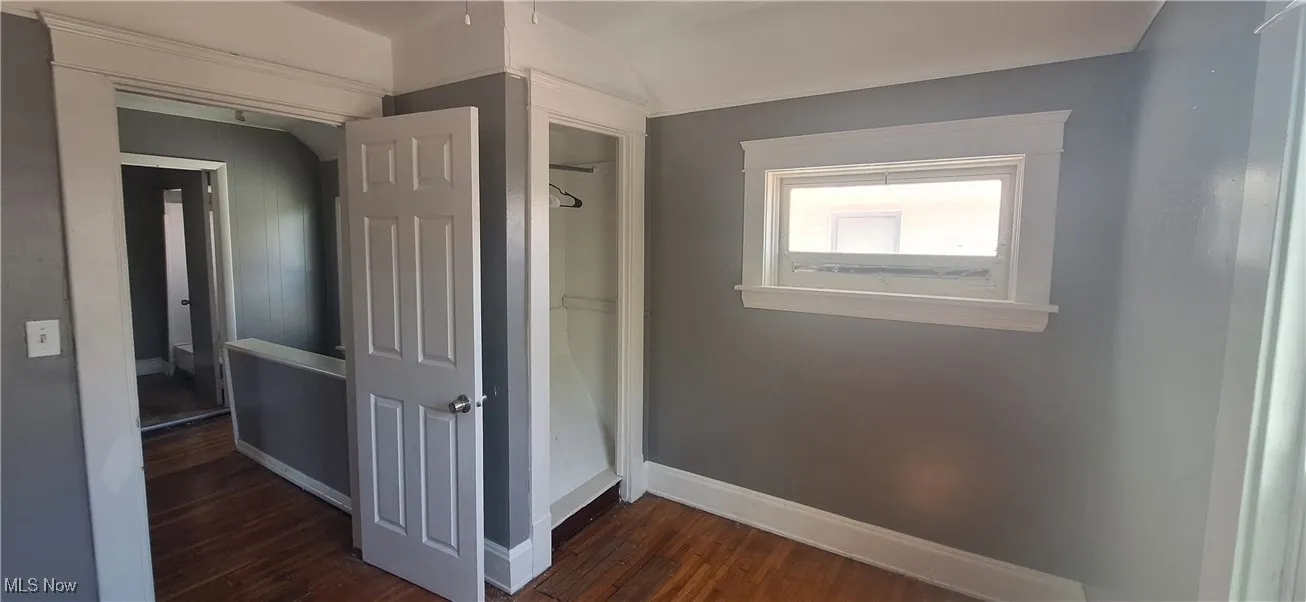 Hallway with baseboards and dark wood-type flooring