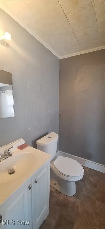 Half bathroom featuring crown molding, toilet, and vanity