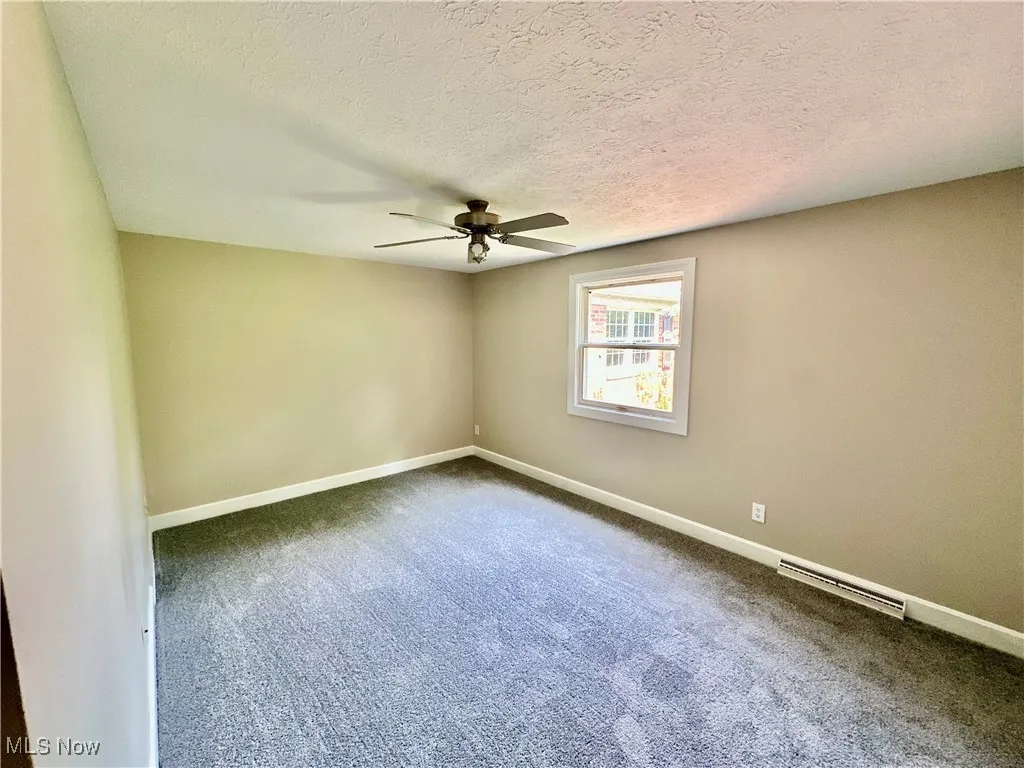 Spare room with dark colored carpet, ceiling fan, a textured ceiling, and baseboard heating