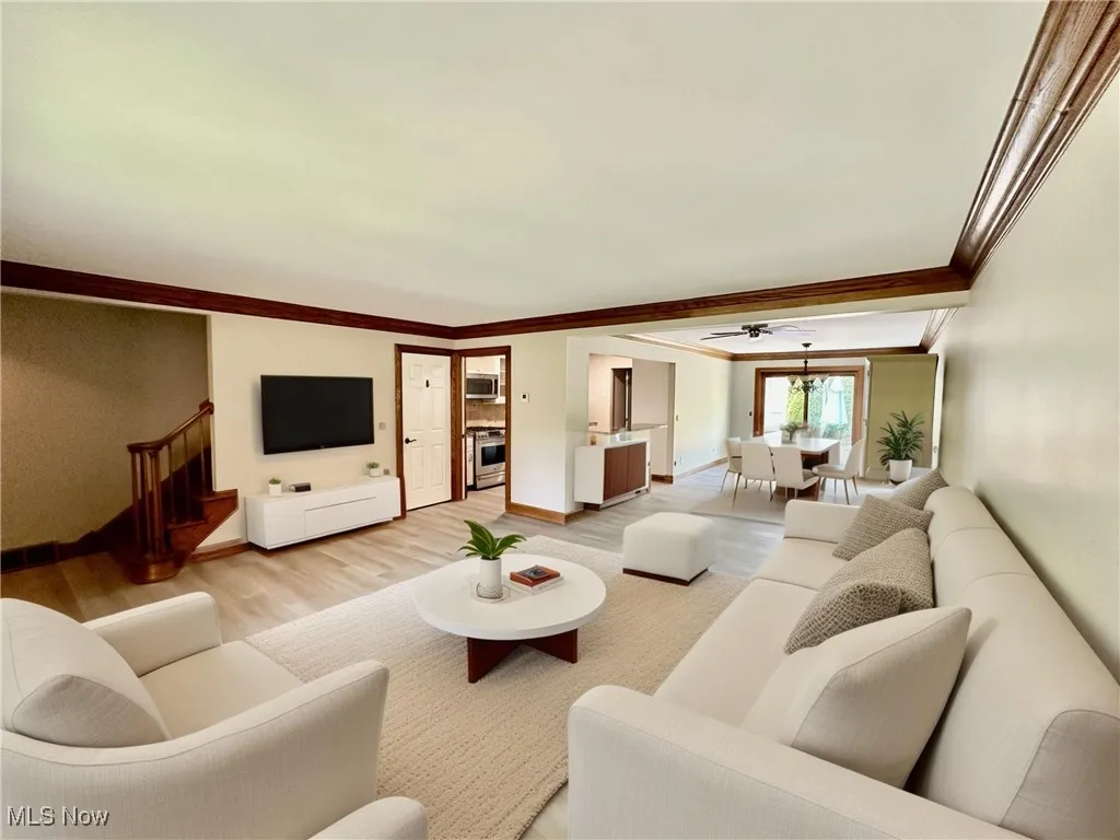 (Virtually Staged) Living area featuring light wood-style flooring, crown molding, and a ceiling fan