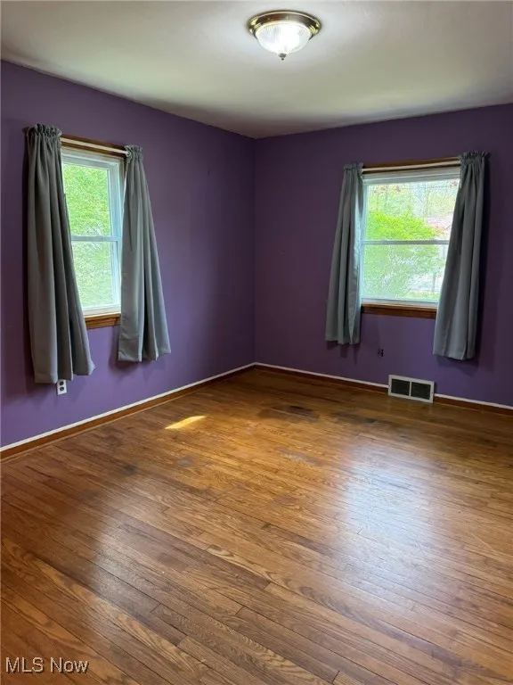 Spare room with baseboards, wood finished floors, and visible vents