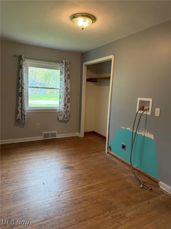 Unfurnished bedroom with visible vents, baseboards, a closet, and hardwood / wood-style floors