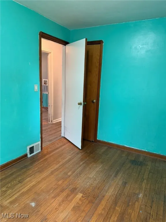 Unfurnished bedroom with visible vents, baseboards, and hardwood / wood-style flooring